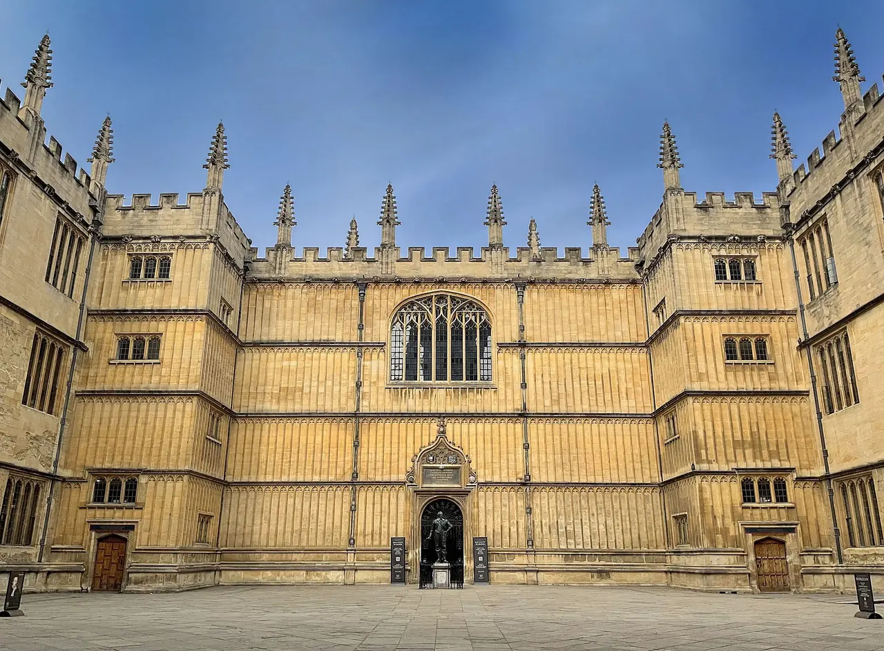 The Old Schools Quadrangle of the Bodleian, honey-coloured stone ranges around a paved courtyard under a blue sky