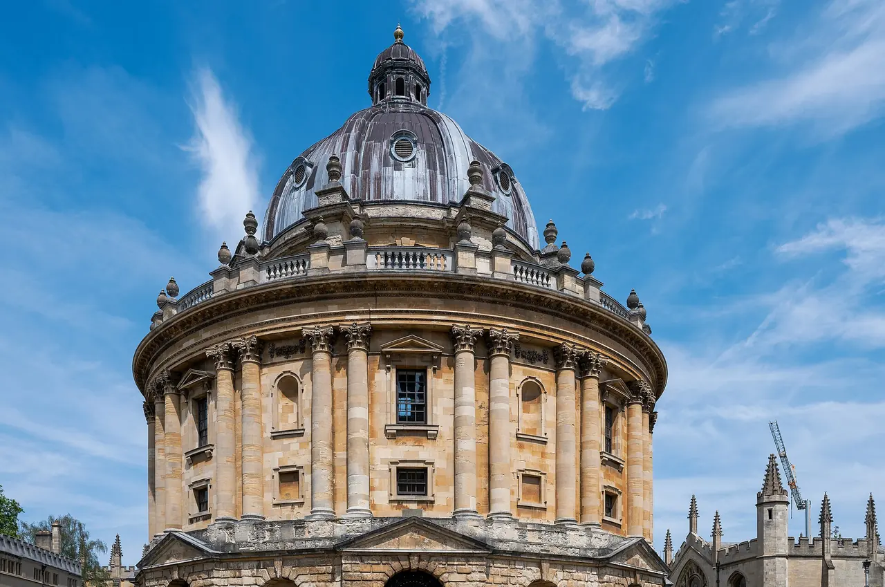 The Radcliffe Camera, a round domed library of golden stone, against a blue sky